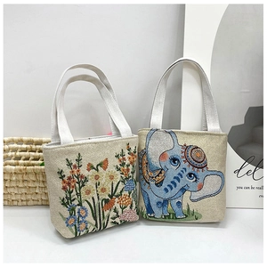 Detailed embroidery of floral and elephant patterns on small beige canvas handbags