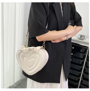 Detail of a heart-shaped cream crossbody bag with ruffle trim and gold metal hardware
