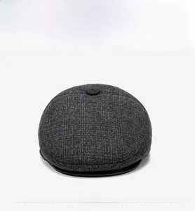 Detailed front view of a dark grey tweed flat cap showing textured wool blend fabric