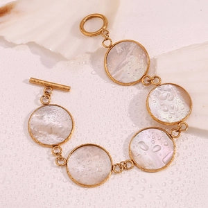 Detail of 18K gold plated stainless steel bracelet with round mother of pearl shell charms