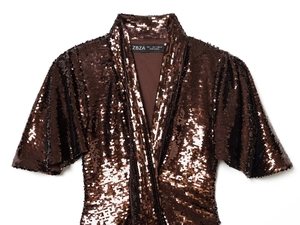 Dettaglio dell'abito con paillettes scollo a V con texture marrone e etichetta