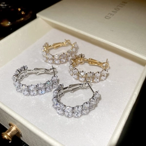 Macro shot of gold and silver C-shaped hoop earrings featuring double rows of zircon stones
