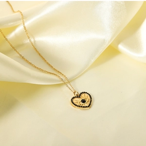 Detailed shot of 18K gold heart pendant with evil eye motif on yellow silk fabric