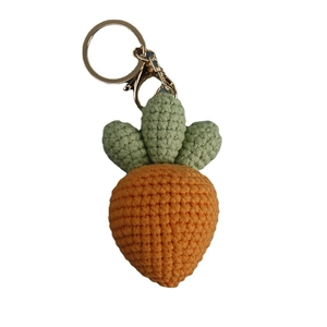 Handmade knitted carrot keychain with orange yarn, green leaves, and gold metal hook