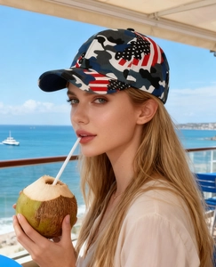Close-up of camouflage baseball cap with US flag design worn by a model at the seaside