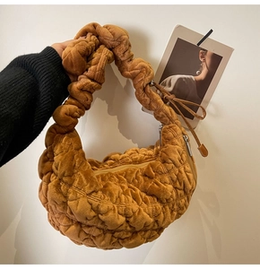 Detailed macro view of the ruched velvet texture and stitching on the caramel cloud bag