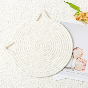 Detailed top view of cat-eared woven cotton rope coaster on a cozy lifestyle background
