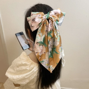 Detail of vintage satin bow hair clip with camellia flower pattern on yellow fabric