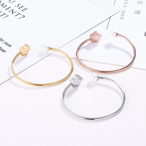 Close-up of three open bracelets in gold, silver, and rose gold with pearls and flowers