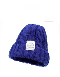 Close-up of blue chunky knit beanie with thick cable patterns and white woven logo label