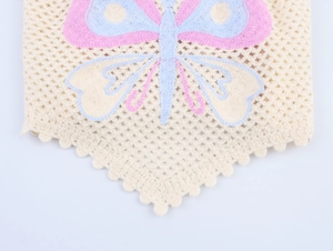 Detailed macro view of crochet knit fabric featuring a colorful butterfly embroidery