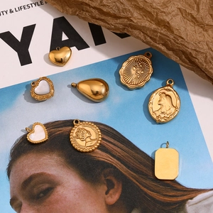 Flat lay of 18K gold plated charms including coin, heart, and shell pendants on vintage paper