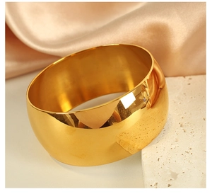 Detailed view of broad gold-plated stainless steel cuff bracelet with mirror-polished finish