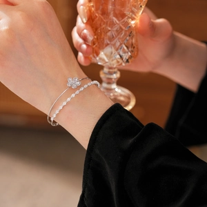 Détail d'un bracelet double couche argenté avec fleurs en zircone au poignet du mannequin