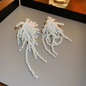 Détails macro de boucles d'oreilles fleurs en perles avec de longs glands sur plateau