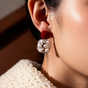 Close-up of 18k gold plated earring with red square resin and pearl inlay on model