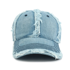 Close-up of distressed light blue denim baseball cap with vintage frayed edges and stitching