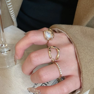 Detailed view of layered gold rings set with a white pearl and sparkling crystals