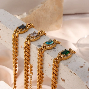 Macro detail of gold Cuban chain bracelets with colorful rectangle gemstones and crystals
