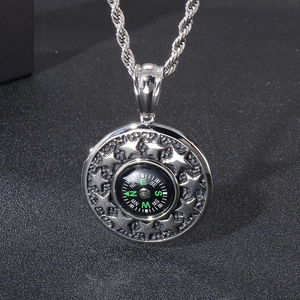 Detail of silver round compass pendant with embossed star patterns and braided chain