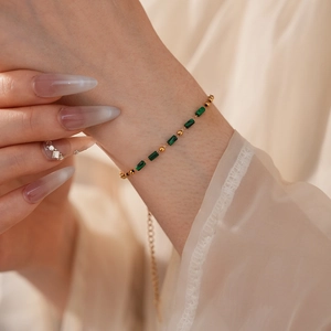 Détail d'un bracelet vintage en chaîne dorée avec pierres de malachite verte au poignet