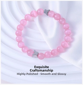 Detailed view of pink cat eye stone beads with silver butterfly pendants on white silk fabric