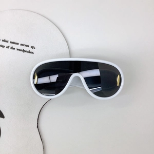 Détail de lunettes de soleil shield blanches avec accents métalliques dorés sur fond blanc
