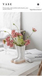 Rain boot shaped ceramic vase in white glossy finish with decorative floral arrangement