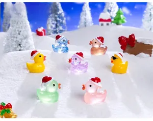 Close-up of colorful mini resin Christmas ducks with hats on a snowy winter background
