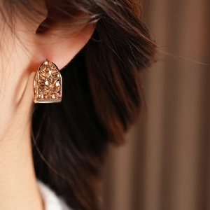 Gros plan de boucles d'oreilles vintage en U avec cristaux champagne en finition or rose