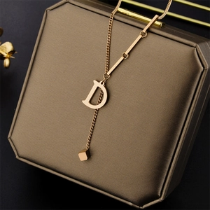 18K gold-plated stainless steel necklace with D-letter pendant and cube charm on box