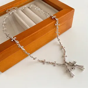 Silver gothic cross link chain necklace draped over a wooden jewelry box edge