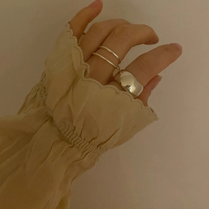 Close-up of minimalist 925 sterling silver layered and irregular textured rings on finger