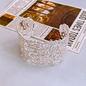 Detailed close-up of wide silver cuff bracelet with irregular lava texture and hollow design