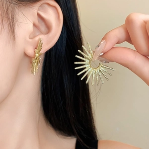 Detailed view of gold sunburst flower earrings on model highlighting the metallic luster
