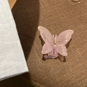 Detailed close-up of pink jelly butterfly hair claw clip with golden metal spring