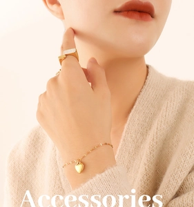 Detail of a gold-plated heart pendant bracelet and geometric ring on a model's hand
