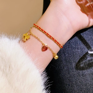 Détail d'un bracelet en corde rouge tressée et chaîne dorée avec pendentif couronne au poignet