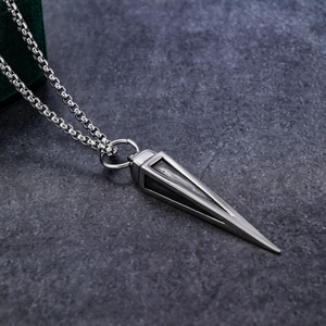 Macro shot of vintage silver triangle cone pendant on textured grey stone background