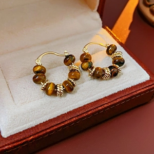 Detailed macro view of gold-plated tiger eye stone beaded earrings in a premium jewelry box