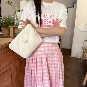 Beige corduroy makeup bag held by a model in a cozy indoor setting with soft textures