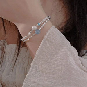 Close-up of double-layer beaded bracelet with silver tubes, pearls and blue beads on wrist