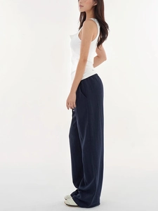 Side view of woman in dark blue wide-leg trousers and a simple white tank top