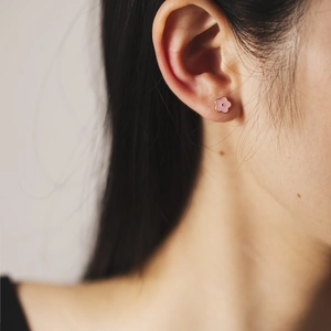 Close-up of pink flower stud earring with enamel finish on a female model