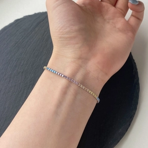 Detailed view of rainbow gradient tennis bracelet with colorful cubic zirconia on model