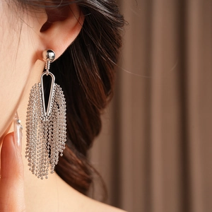 Detail of silver long tassel earrings with metal bead chains on a female model
