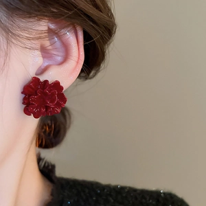 Close-up of elegant deep red pleated flower earrings with glossy layered petal detail