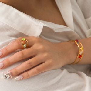 Detail of luxury gold open ring and bracelet set with colorful stones on a model