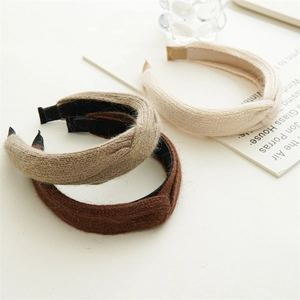 Close-up of knit headbands in cream, khaki, and brown on a minimalist white desk