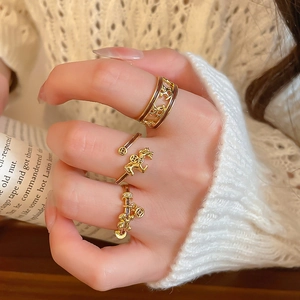 Detailed close-up of vintage gold-plated horse rings with brown enamel on a female hand